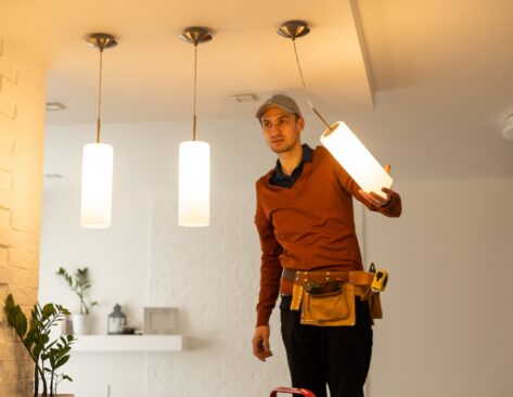 Electrician man working on exterior light, install LED replacement lamp at home. Maintenance concept.